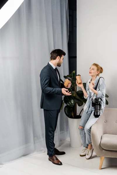 Photographer and model holding paper cups and talking in photo studio — Stock Photo