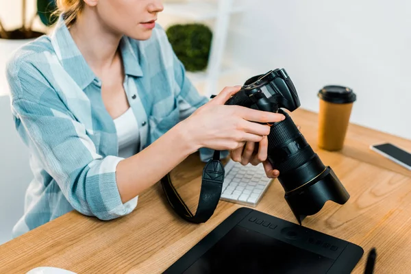 Fotografía recortada de la joven fotógrafa trabajando con la cámara en la oficina - foto de stock