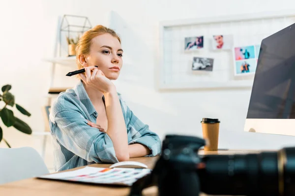 Pensive young retoucher using desktop computer and drawing tablet in office — Stock Photo