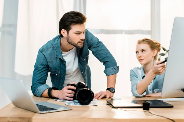 Fotógrafos jóvenes profesionales que utilizan computadoras de escritorio y discutir fotos - foto de stock