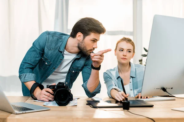 Jovens fotógrafos que utilizam dispositivos digitais e retocam fotos no local de trabalho — Fotografia de Stock