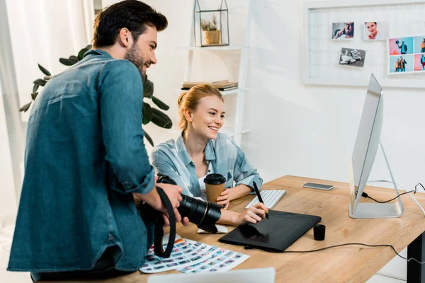 Sourire de jeunes photographes utilisant des appareils numériques et retoucher des photos sur le lieu de travail — Photo de stock