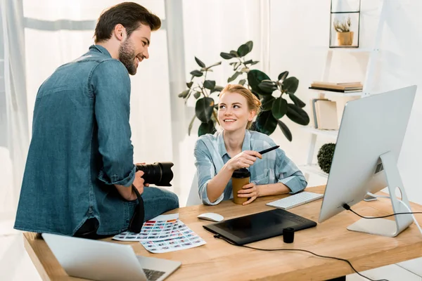 Smiling young photographers working with digital devices at workplace — Stock Photo