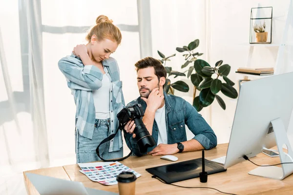 Fotógrafos jóvenes profesionales que utilizan la cámara fotográfica mientras trabajan juntos en la oficina - foto de stock