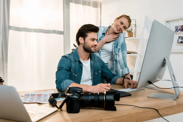 Giovani ritoccatori professionisti sorridenti che lavorano insieme in ufficio — Foto stock