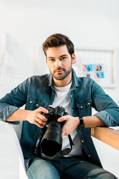 Schöner junger Fotograf mit Fotokamera im Büro — Stockfoto