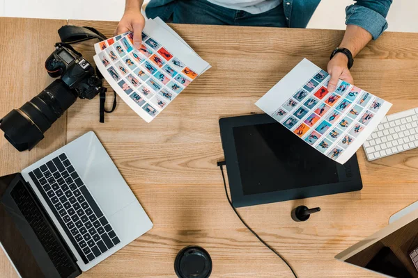 Cropped shot of photographer holding photos and working at desk — Stock Photo