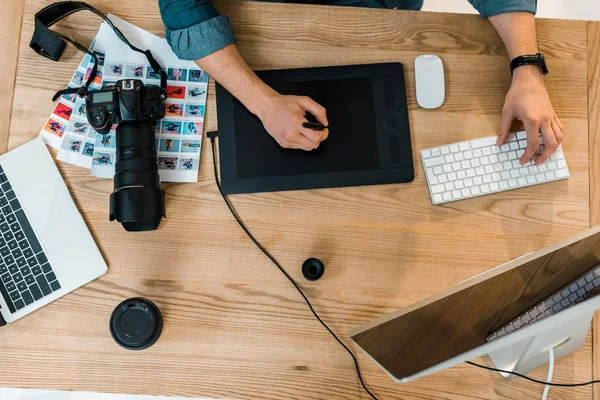 Vista dall'alto parziale del giovane ritoccatore che lavora con computer desktop e tablet da disegno — Foto stock