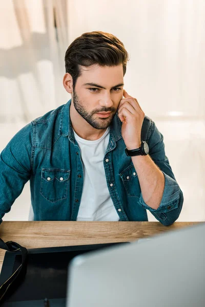 Handsome young man retouching photos at workplace — Stock Photo