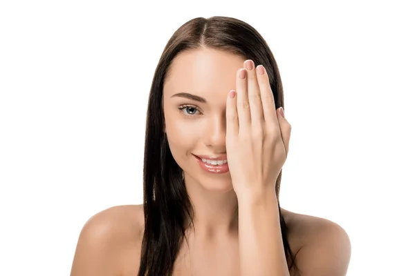 Beautiful naked woman closing eye with hand and smiling at camera isolated on white — Stock Photo