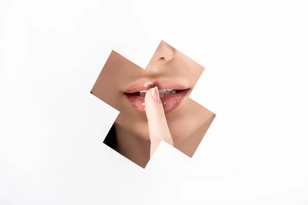 Cropped shot of girl gesturing for silence through cross shaped hole on white — Stock Photo