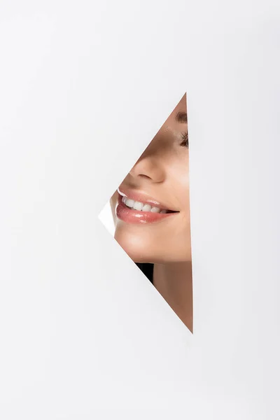 Cropped shot of beautiful girl smiling through hole on white — Stock Photo