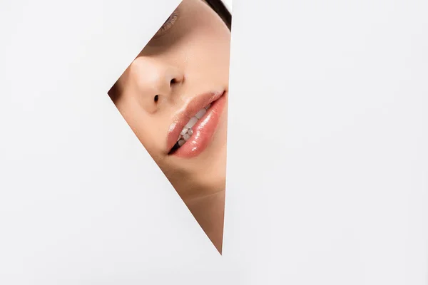 Cropped shot of young woman biting lip through hole on white — Stock Photo