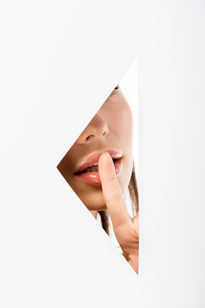 Abgeschnittene Aufnahme einer jungen Frau, die durch ein Loch auf Weiß zum Schweigen gestikuliert — Stockfoto