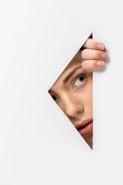 Young woman looking away through hole on white — Stock Photo