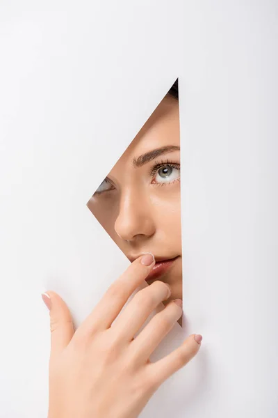 Pensive girl touching lips through hole on white — Stock Photo