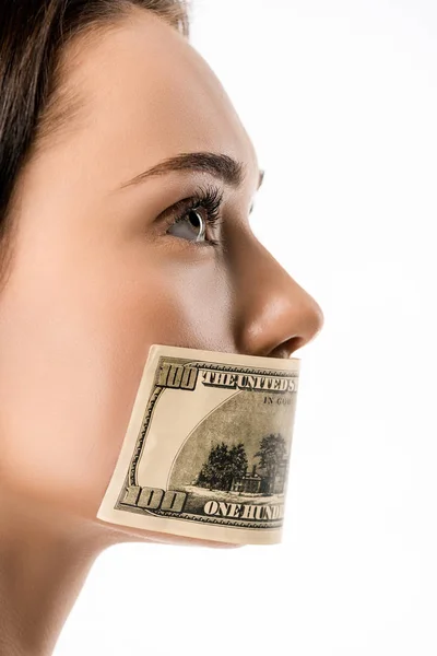 Vista de cerca de la mujer con billete de dólar en la boca mirando hacia otro lado aislado en blanco - foto de stock