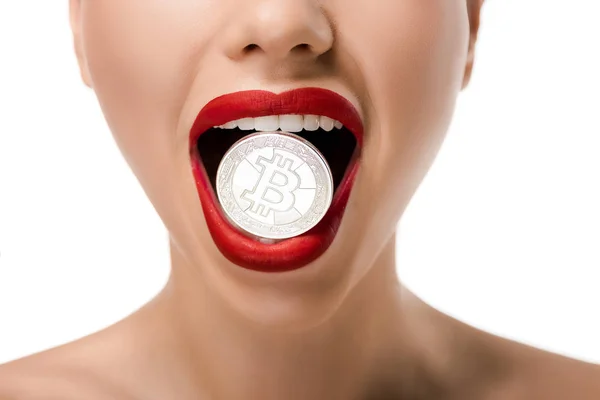 Recortado disparo de chica con labios rojos sosteniendo bitcoin en los dientes aislados en blanco - foto de stock