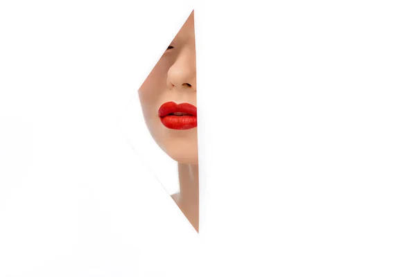 Bela jovem mulher com lábios vermelhos, vista através do buraco no branco — Fotografia de Stock