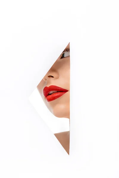 Beautiful young woman red red lips looking away, view through hole on white — Stock Photo