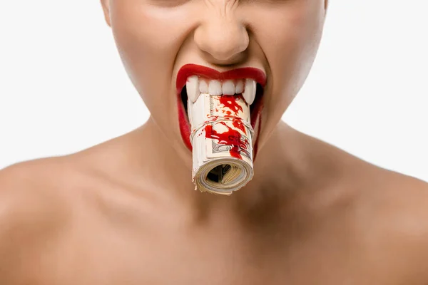 Обрезанный снимок девушки с вампирскими клыками, держащей свернутые доллары с кровью во рту, изолированной на белом — стоковое фото