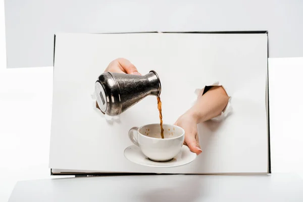 Recortado disparo de la mujer vertiendo café en la taza a través de agujeros en blanco - foto de stock