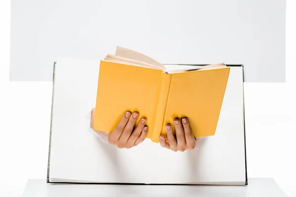 Abgeschnittene Aufnahme einer Frau, die Buch durch Löcher auf Weiß hält — Stockfoto