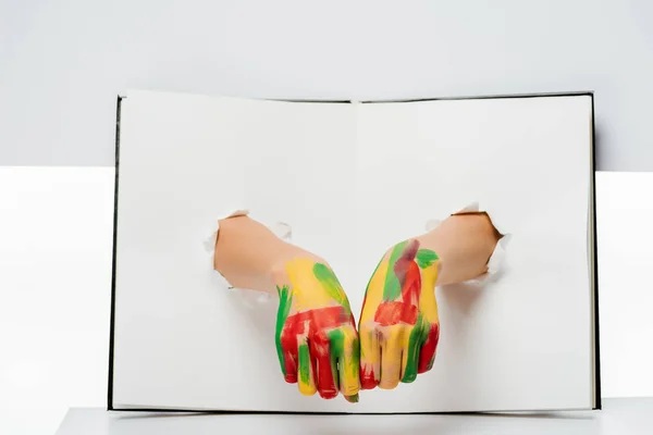 Recortado tiro de las manos femeninas en pintura a través de agujeros en blanco - foto de stock