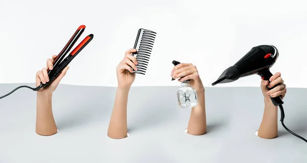 Plan recadré de femmes tenant des outils de coiffure à travers des trous sur blanc — Photo de stock