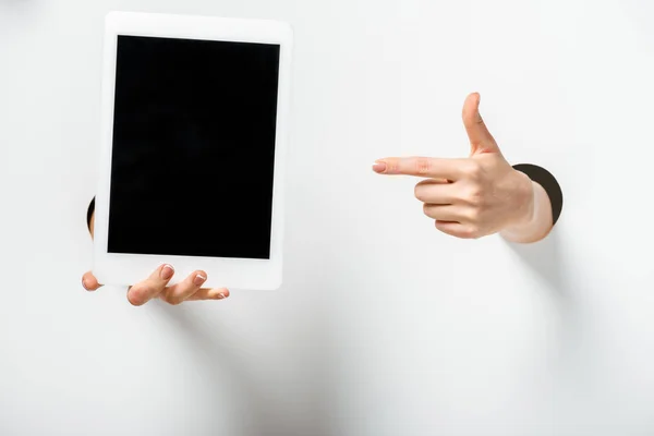 Image recadrée de la femme pointant sur la tablette avec écran blanc à travers des trous sur blanc — Photo de stock