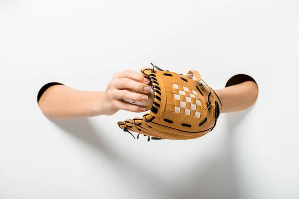 Image recadrée d'une sportive tenant un gant de baseball et une balle à travers des trous sur du blanc — Photo de stock