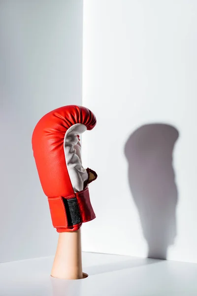 Cropped image of woman showing hand in red boxing glove through hole on white — Stock Photo