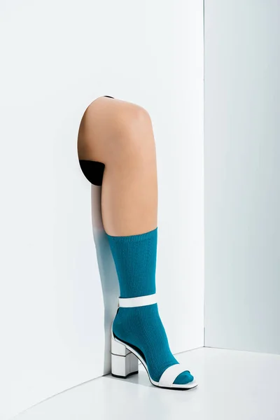 Cropped image of girl showing leg in stylish turquoise sock and white high heel in hole on white — Stock Photo