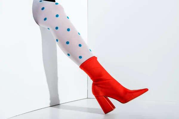 Image recadrée de fille montrant jambe en collants blancs à pois bleus et chaussure rouge dans le trou sur blanc — Photo de stock