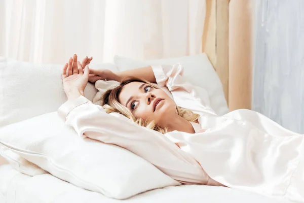 Вибірковий фокус жінки в піжамі розслабляється в ліжку в ранковий час вдома — стокове фото