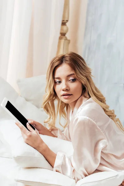 Femme blonde utilisant une tablette numérique avec écran blanc au lit pendant le matin à la maison — Photo de stock