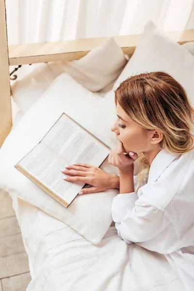 Hochwinkelaufnahme des Mädchens im Pyjama, das morgens zu Hause Buch im Bett liest — Stock Photo