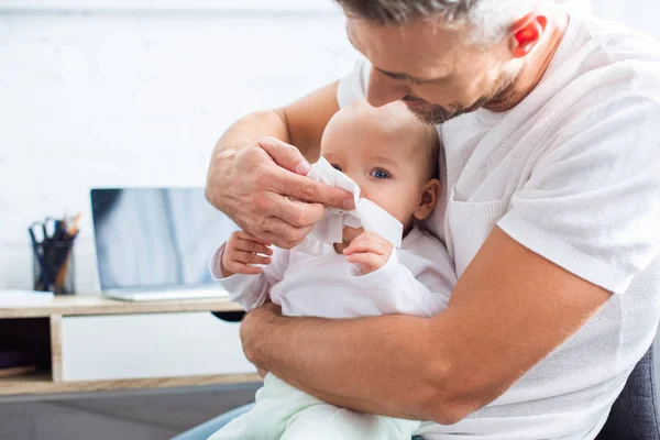 Pai esfregando corrimento nariz de adorável bebê filha com guardanapo em casa — Fotografia de Stock