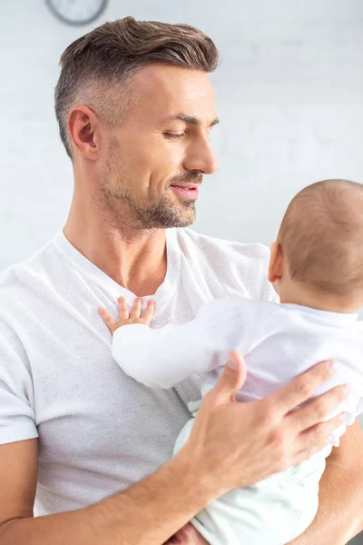 Hermoso padre sosteniendo bebé en casa - foto de stock