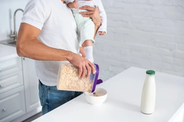 Cropped view of father holding baby and preparing breakfast — Stock Photo