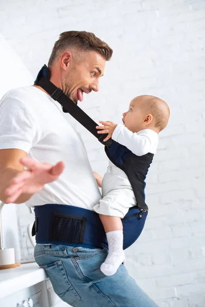 Drôle papa montrant la langue à bébé à la maison — Photo de stock