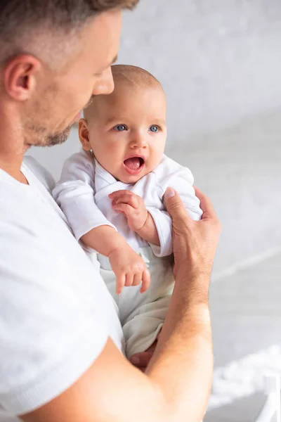 Selective focus of surprised baby in hands of father — Stock Photo