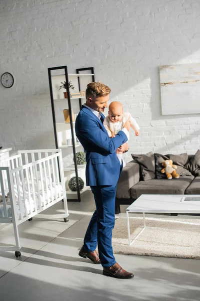 Allegro uomo d'affari che tiene la figlia neonata in soggiorno — Foto stock