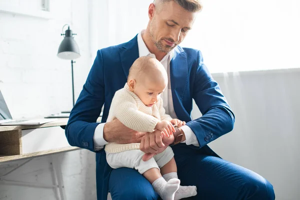 Cute baby touching watch of handsome father in suit — Stock Photo