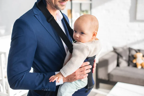 Vista recortada del padre sosteniendo a la hija bebé en el portabebés - foto de stock