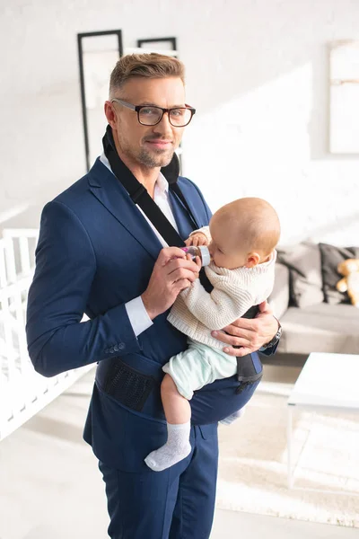 Allegro uomo d'affari che alimenta la figlia neonata dalla bottiglia — Foto stock