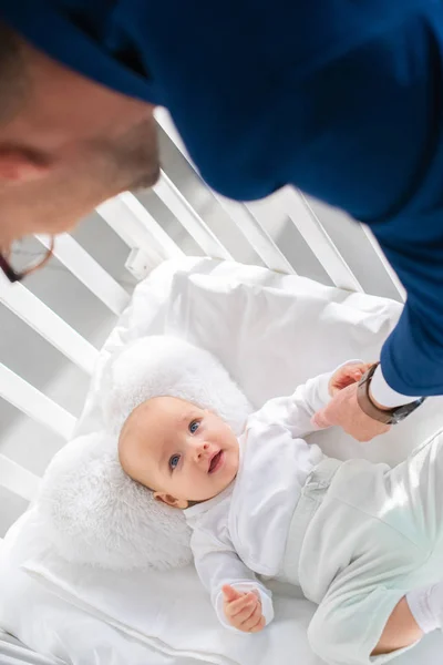 Visão aérea do pai no terno segurando a mão da filha infantil no berço do bebê — Fotografia de Stock