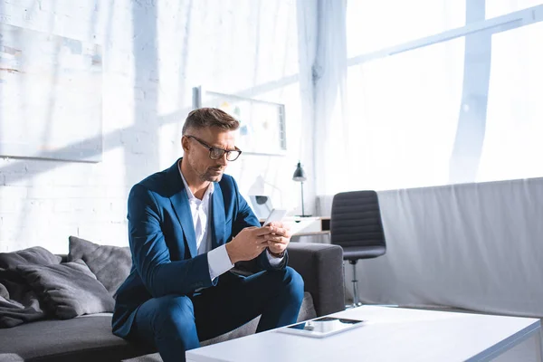 Homme d'affaires concentré utilisant smartphone dans le salon — Photo de stock