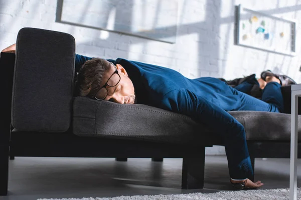 Hombre de negocios borracho durmiendo en el sofá en gafas - foto de stock