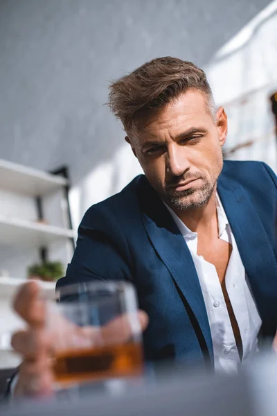 Selective focus of drunk businessman holding glass of whiskey — Stock Photo